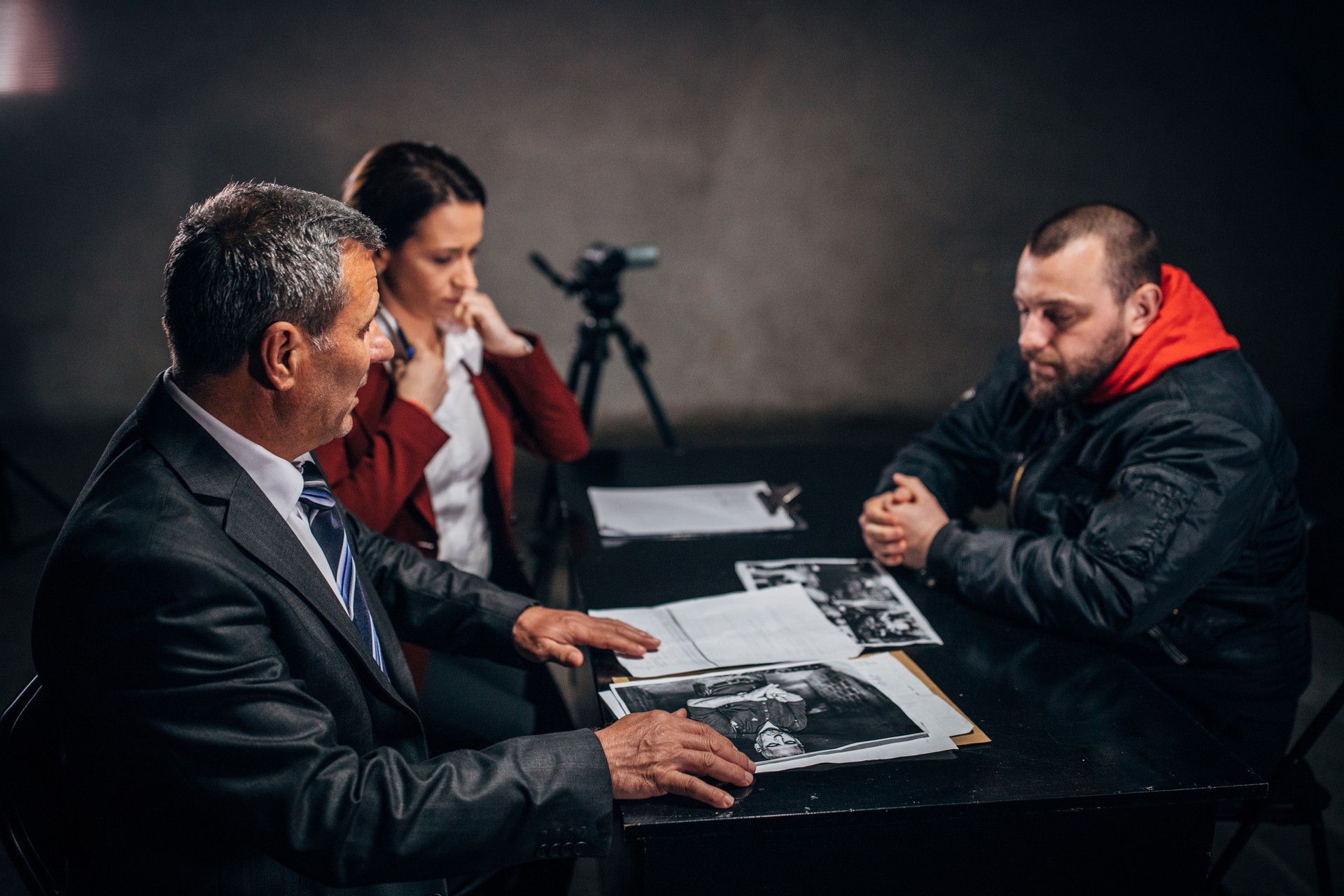Detectives and male prisoner in interrogation room